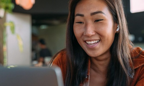 a woman smiling while working on laptop