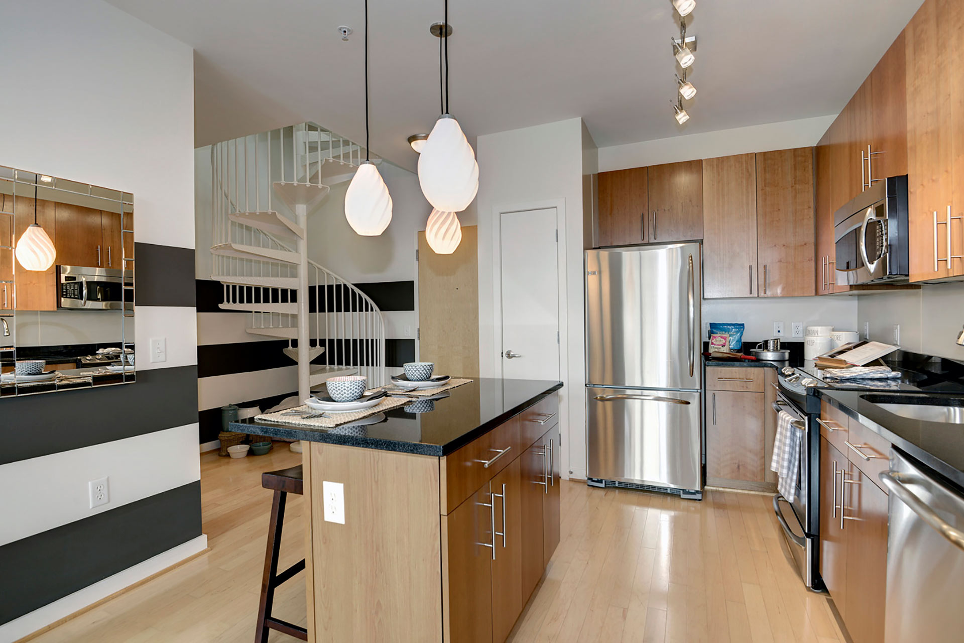 Angled view of model unit kitchen with spiral staircase to loft level in background