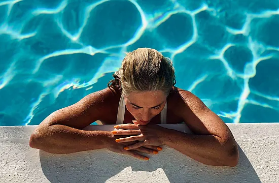 mature woman relaxing on a swimming pool ledge