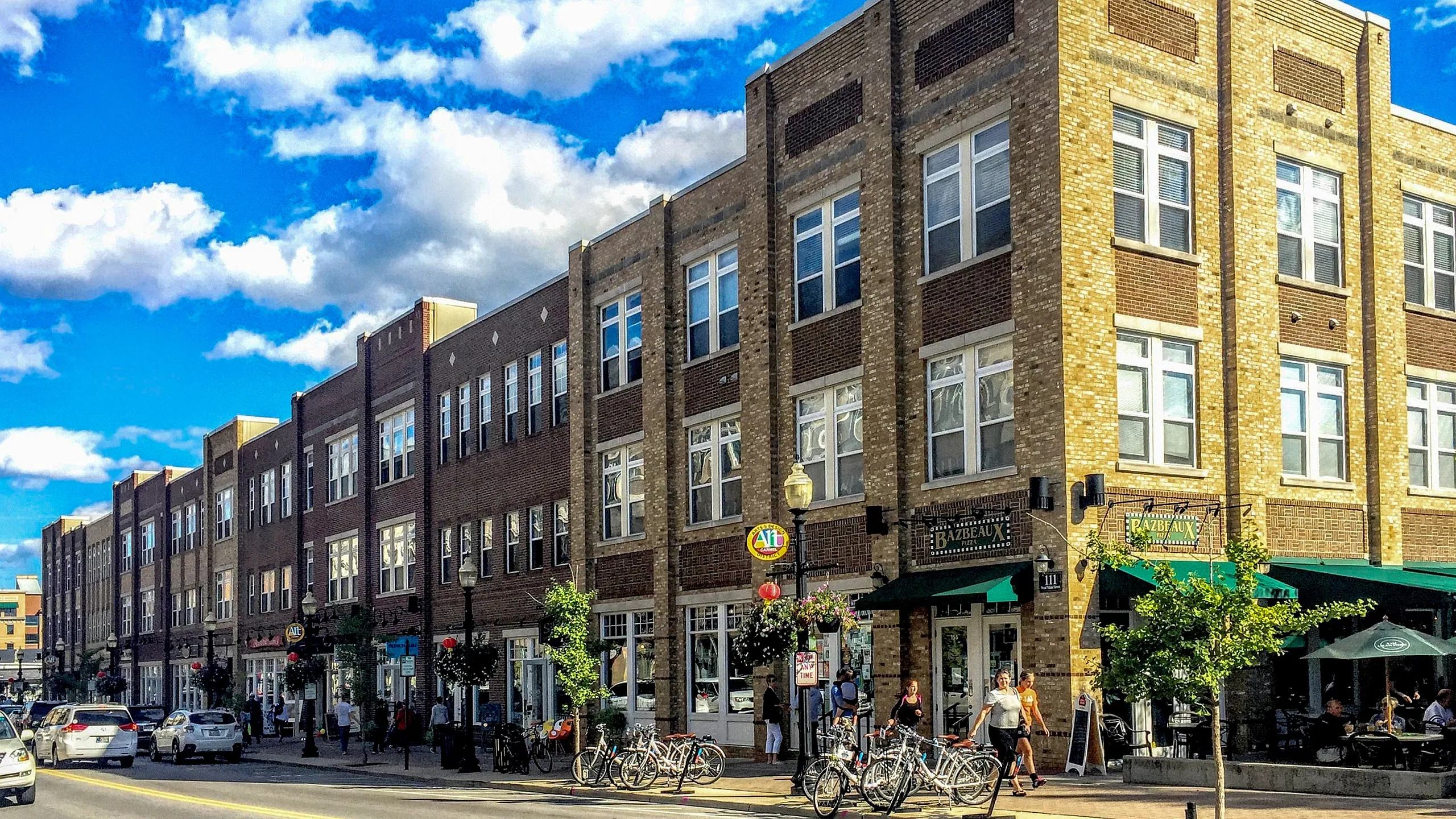 Charming urban apartments with beautiful brick facade, vibrant street life, and cozy outdoor dining spaces.