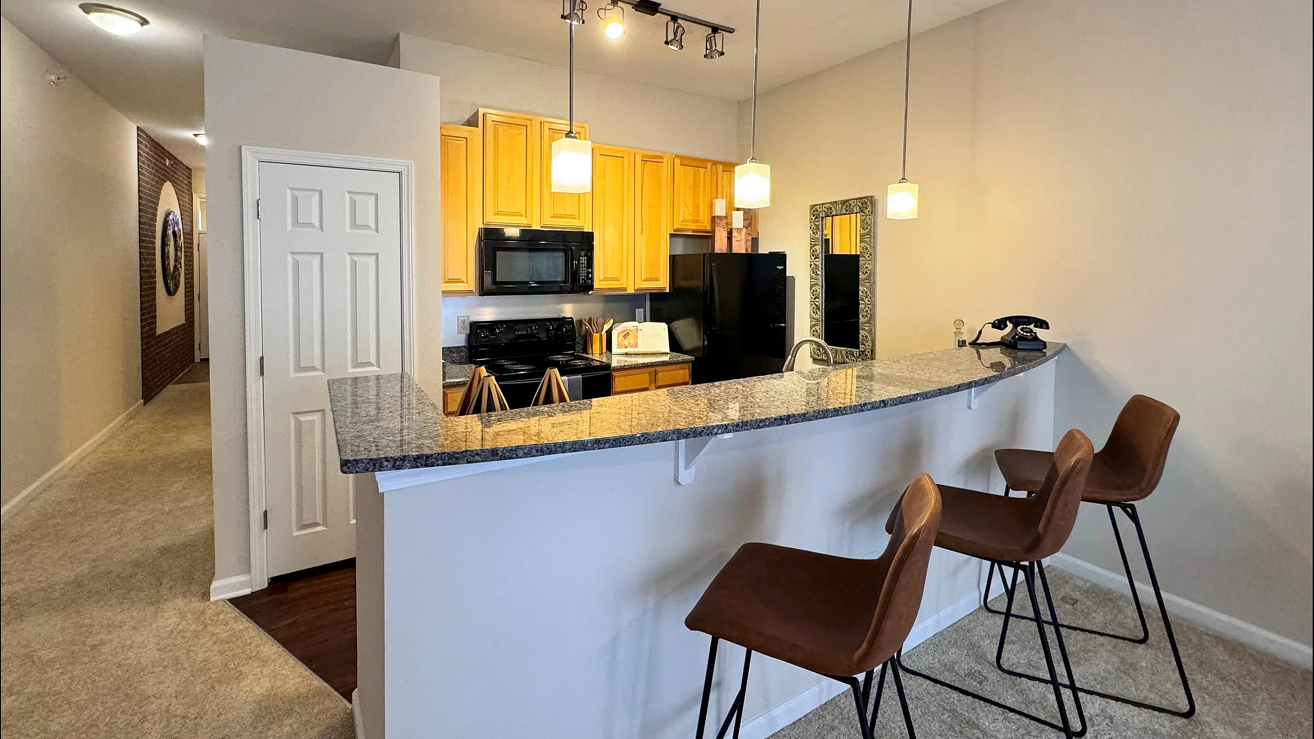Modern kitchen with granite countertops, stylish lighting, and sleek bar seating creating an inviting open-concept space.