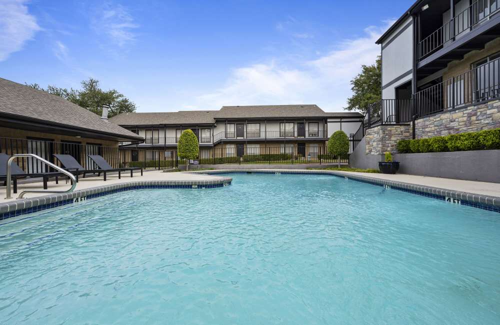 A sparkling blue pool with lounge chairs around the edge at Lakeridge Heights in Dallas, Texas