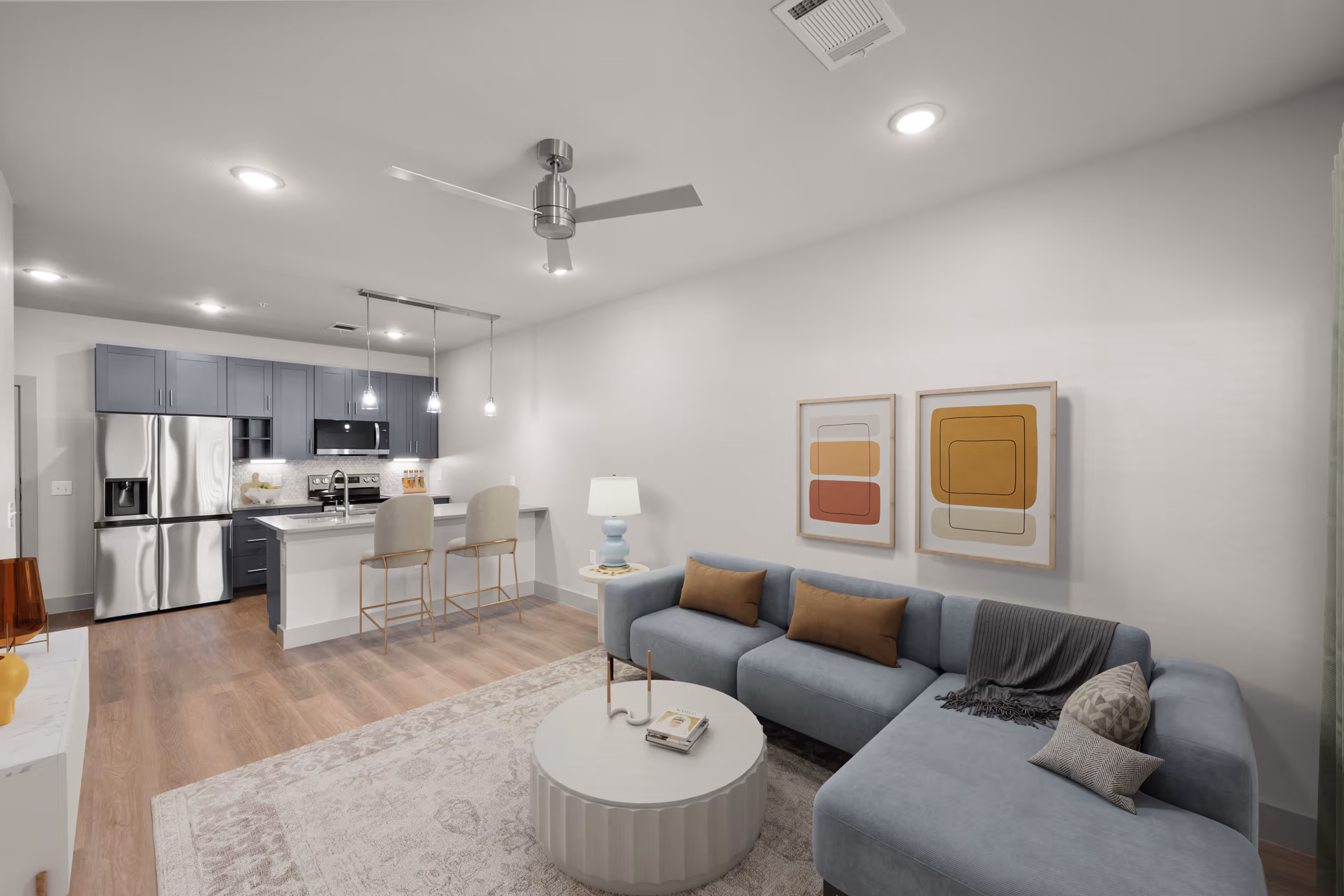 Living room with a couch and Kitchen with grey cabinets plank flooring and stainless steel appliances