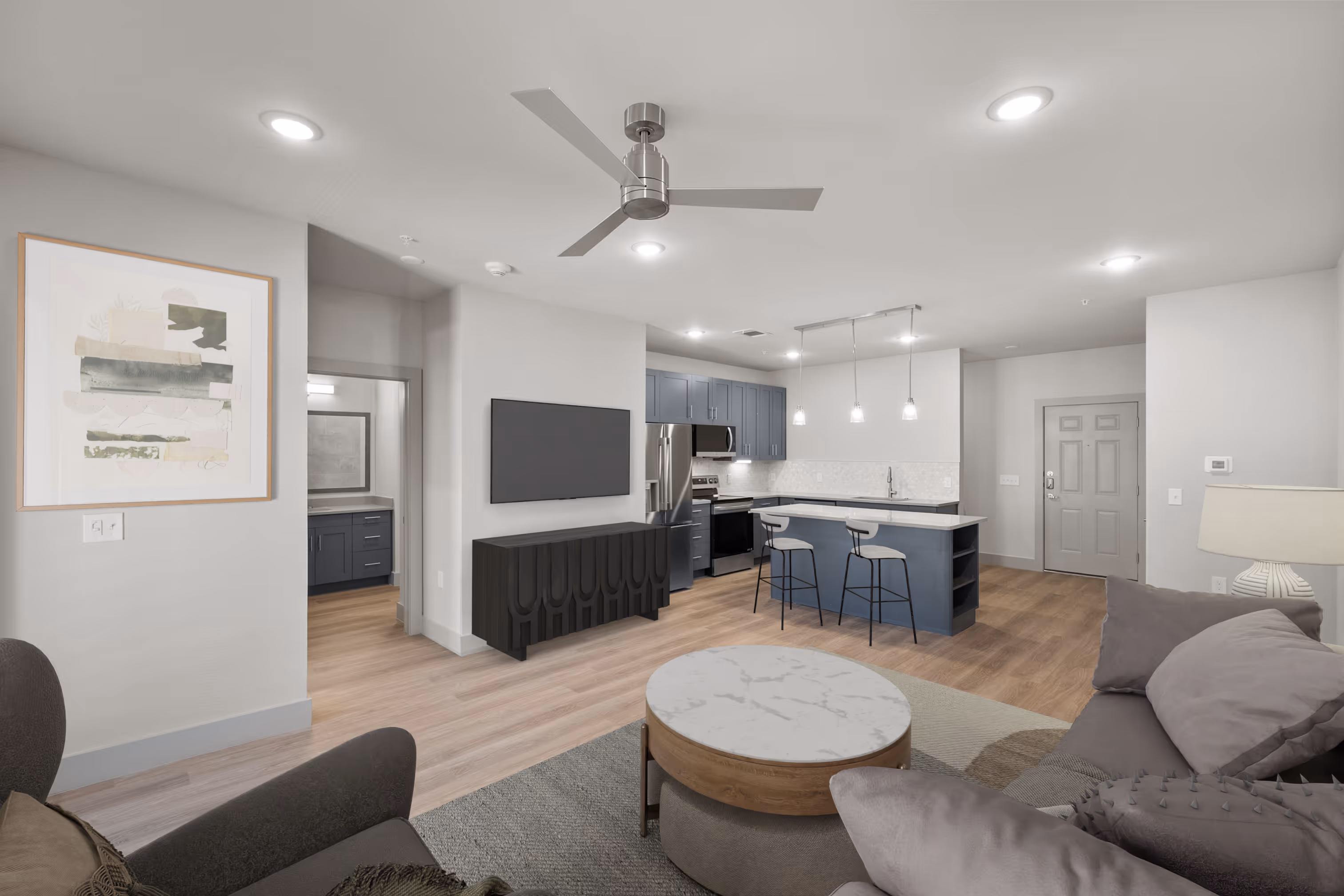 Living room with a couch and Kitchen with grey cabinets island and plank flooring