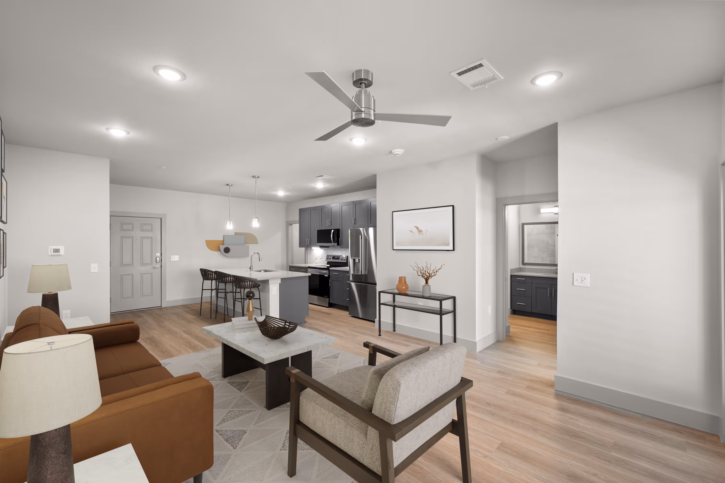 Living room with a couch and Kitchen with grey cabinets plank flooring and stainless steel appliances
