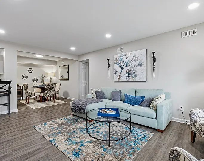 Elegant open-concept living room with a cozy sectional sofa, modern art, stylish decor, and a chic dining area, ideal for entertaining.