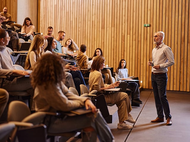 christopher newport university Engaging lecture hall scene with attentive students and a passionate lecturer in a modern, wood-paneled auditorium.