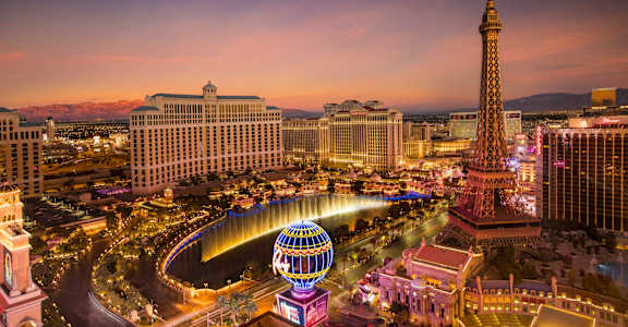 A cityscape with a tall tower and a large Ferris wheel.