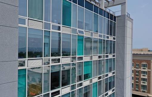A modern building with large glass windows reflecting the sky and other buildings.