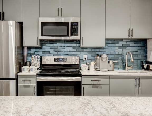 A kitchen with a stove, refrigerator, and microwave.