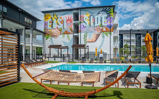 A pool area with a mural on the wall and lounge chairs.