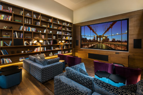media room with couches, large tv and book shelf