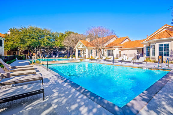 a swimming pool with chairs around it in front of a house at The Olivine, Texas