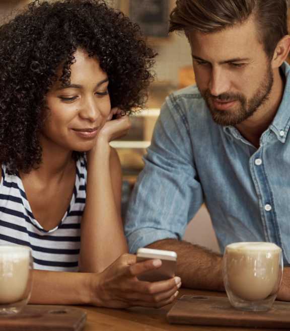 A man and a woman are sitting at a table with a glass of milkshake in front of them.