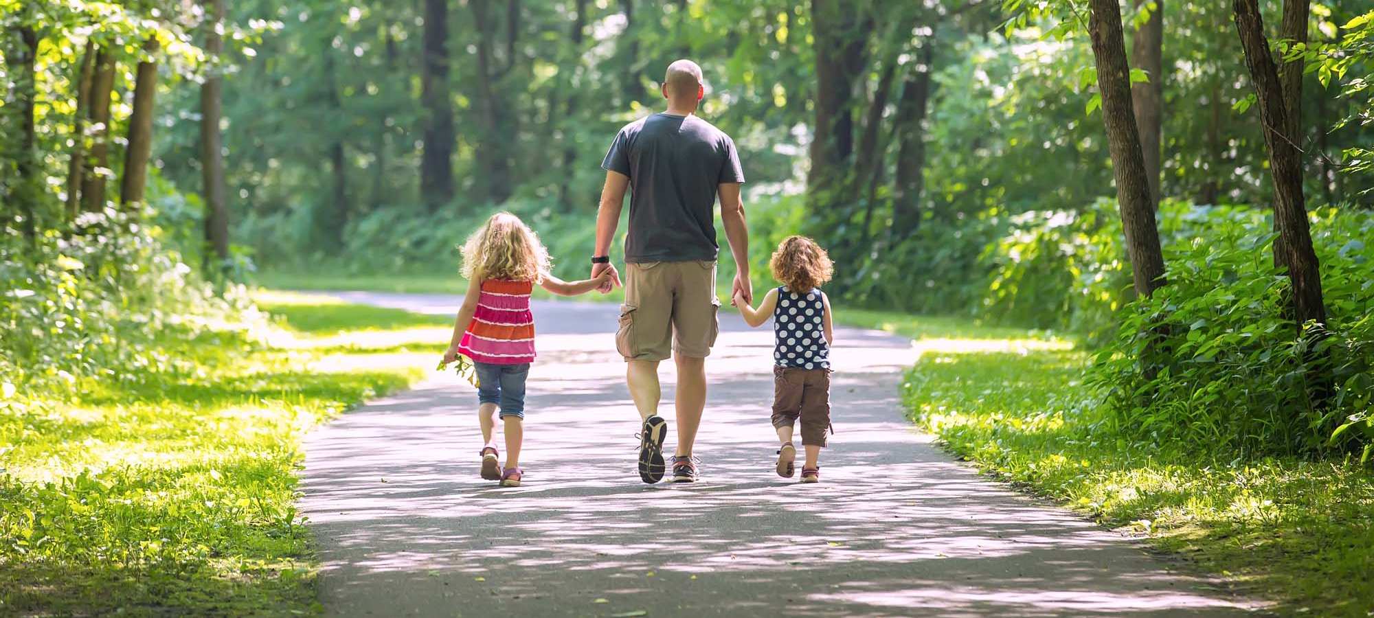 Resident father walking with her kids in a park near The Waterford in Morrisville, North Carolina