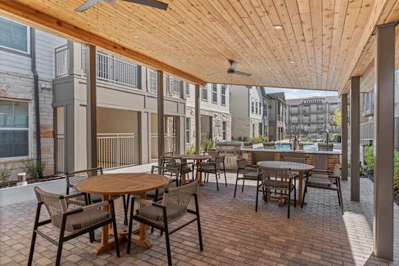 A patio with a table and chairs is covered by a wooden roof.