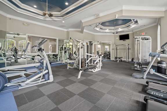 A gym with a variety of equipment including treadmills, weights, and exercise machines at The Grand Reserve at Tampa Palms Apartments, Tampa, FL