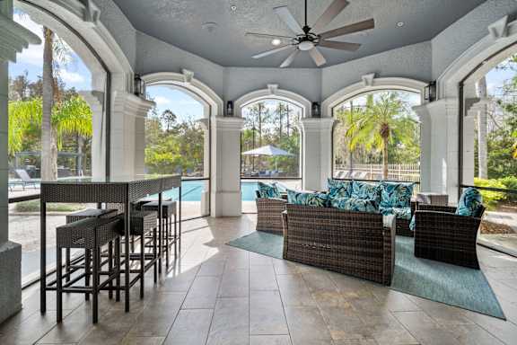 A patio with a table and chairs overlooking a pool at The Grand Reserve at Tampa Palms Apartments, Florida