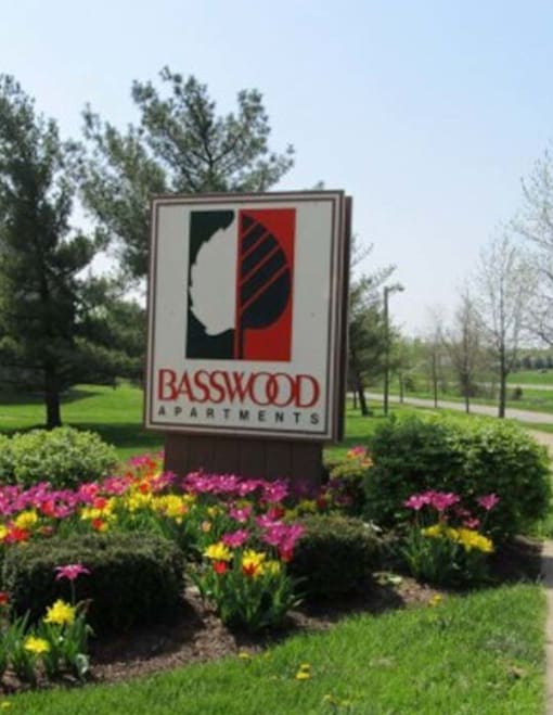A Basswood Apartments sign is in front of a green lawn.