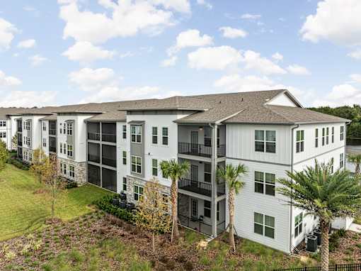 A white apartment building with balconies and a green lawn in front. at Terrassa Luxury Apartments, St. Augustine, Florida
