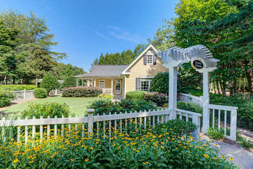 A house with a white fence and a white archway with a sign on it.