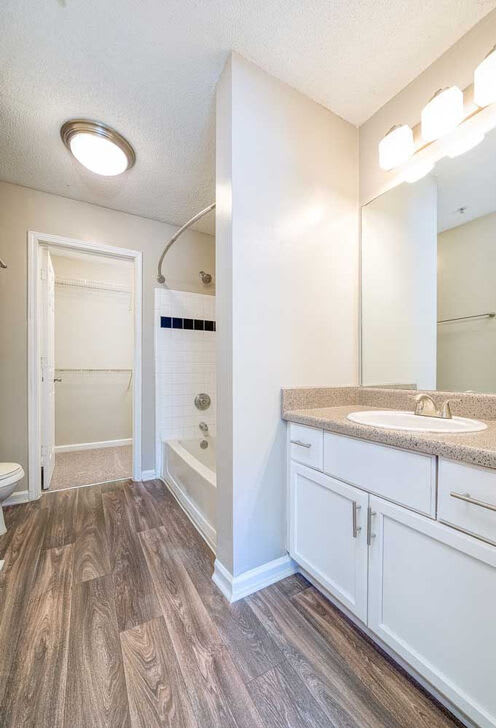 A bathroom with a sink, mirror, and wood flooring.