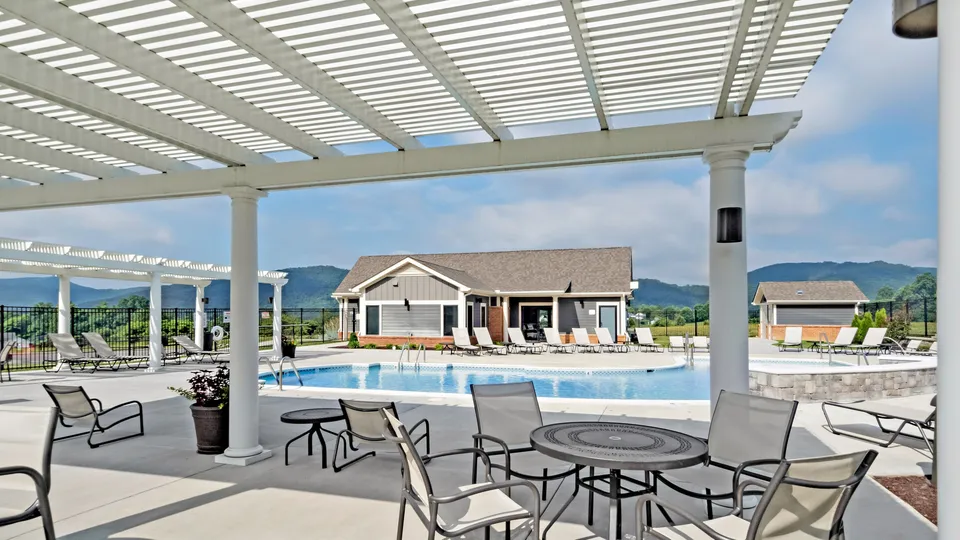 Elegant poolside area with lounge chairs, a covered pergola, and scenic mountain views.