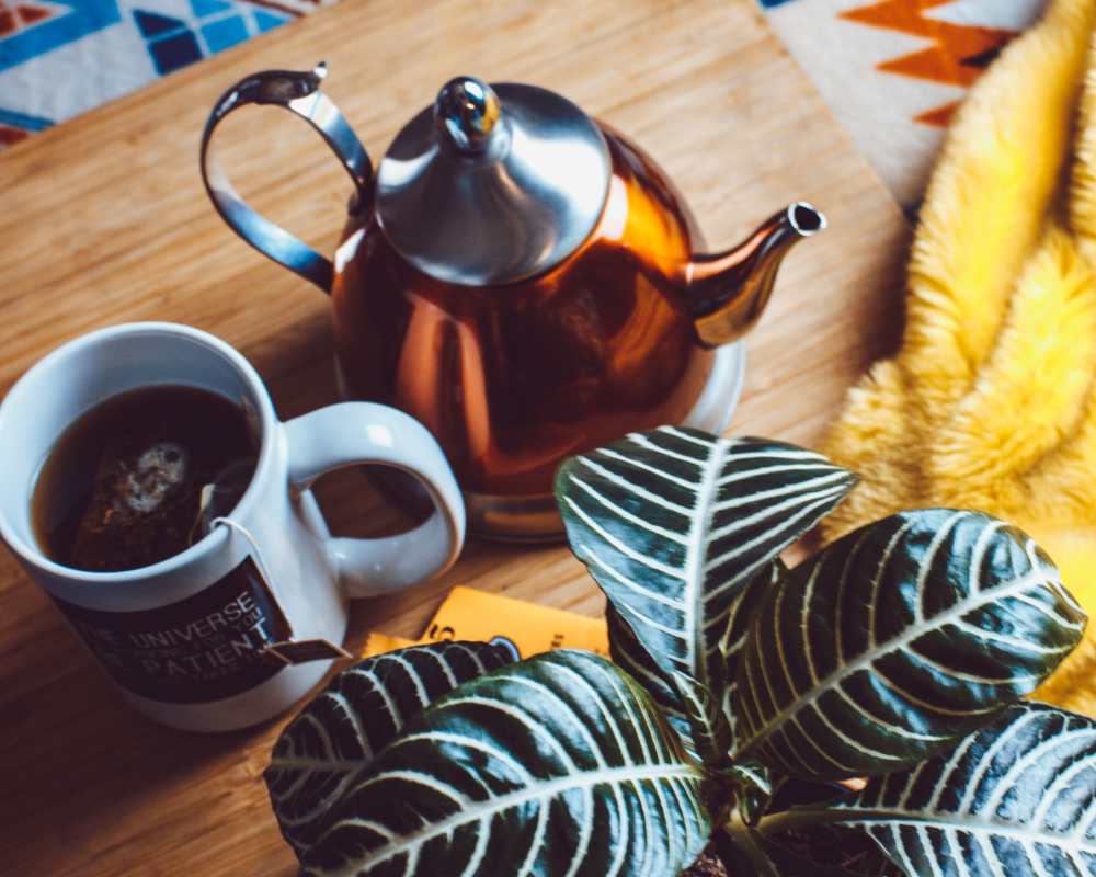 Copper-colored Teapot and a White Mug Filled with Dark Tea at Raven South End in Charlotte, North Carolina