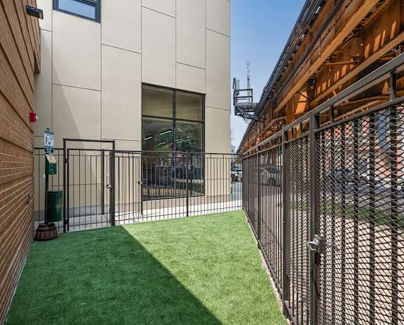 A small fenced in area with a green lawn.