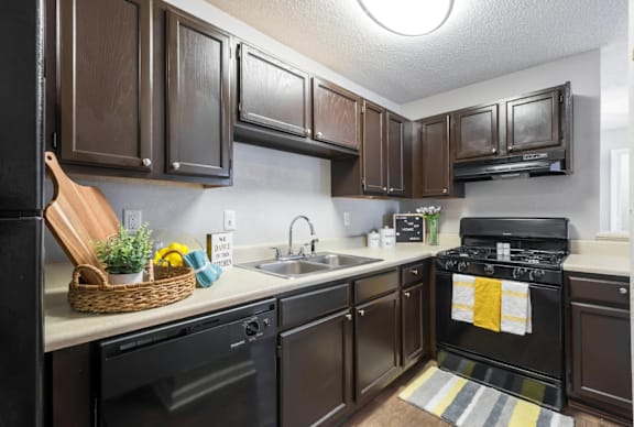 A kitchen with dark brown cabinets and black appliances.