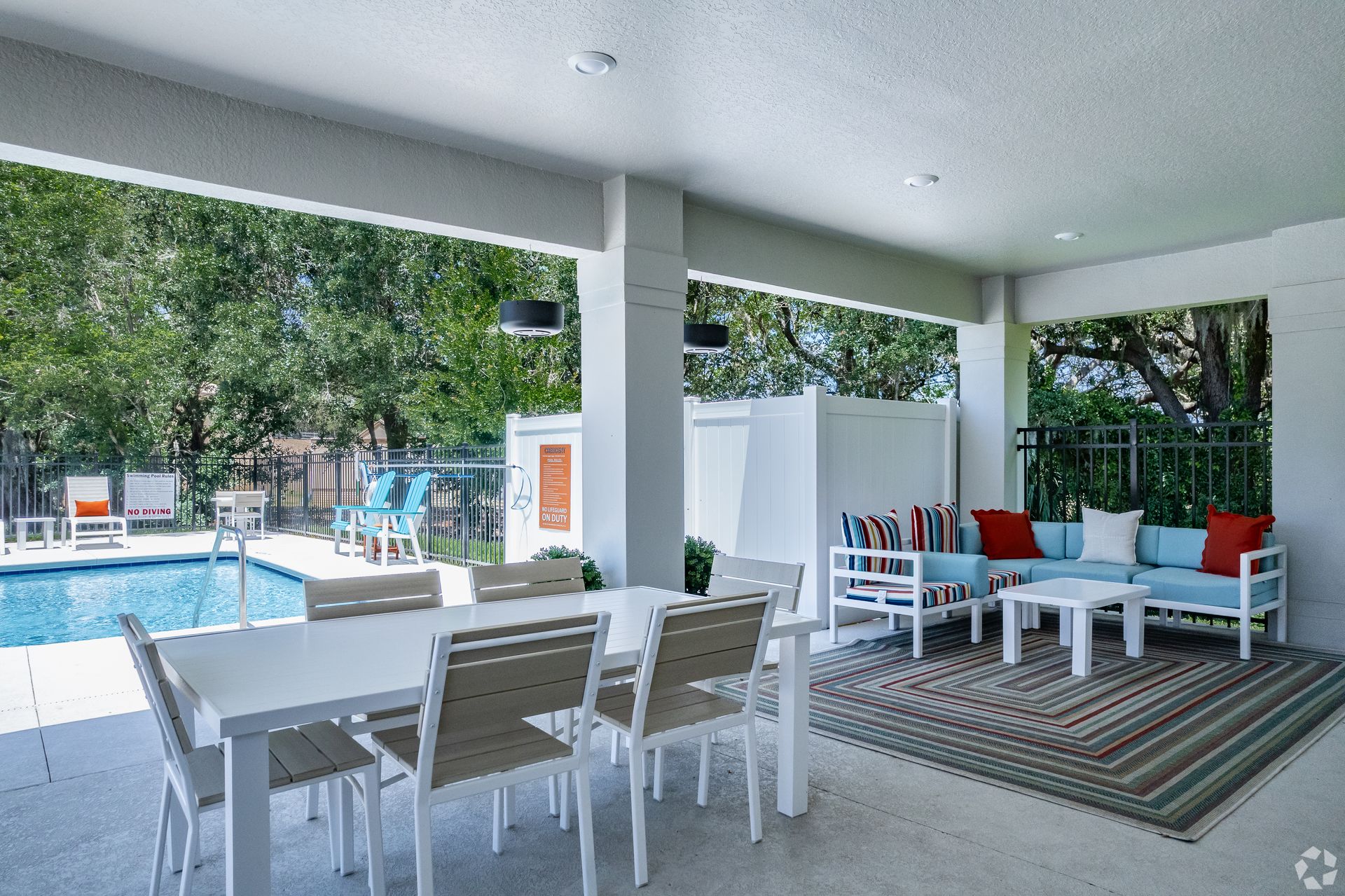 A patio with a table and chairs and a couch next to a pool.
