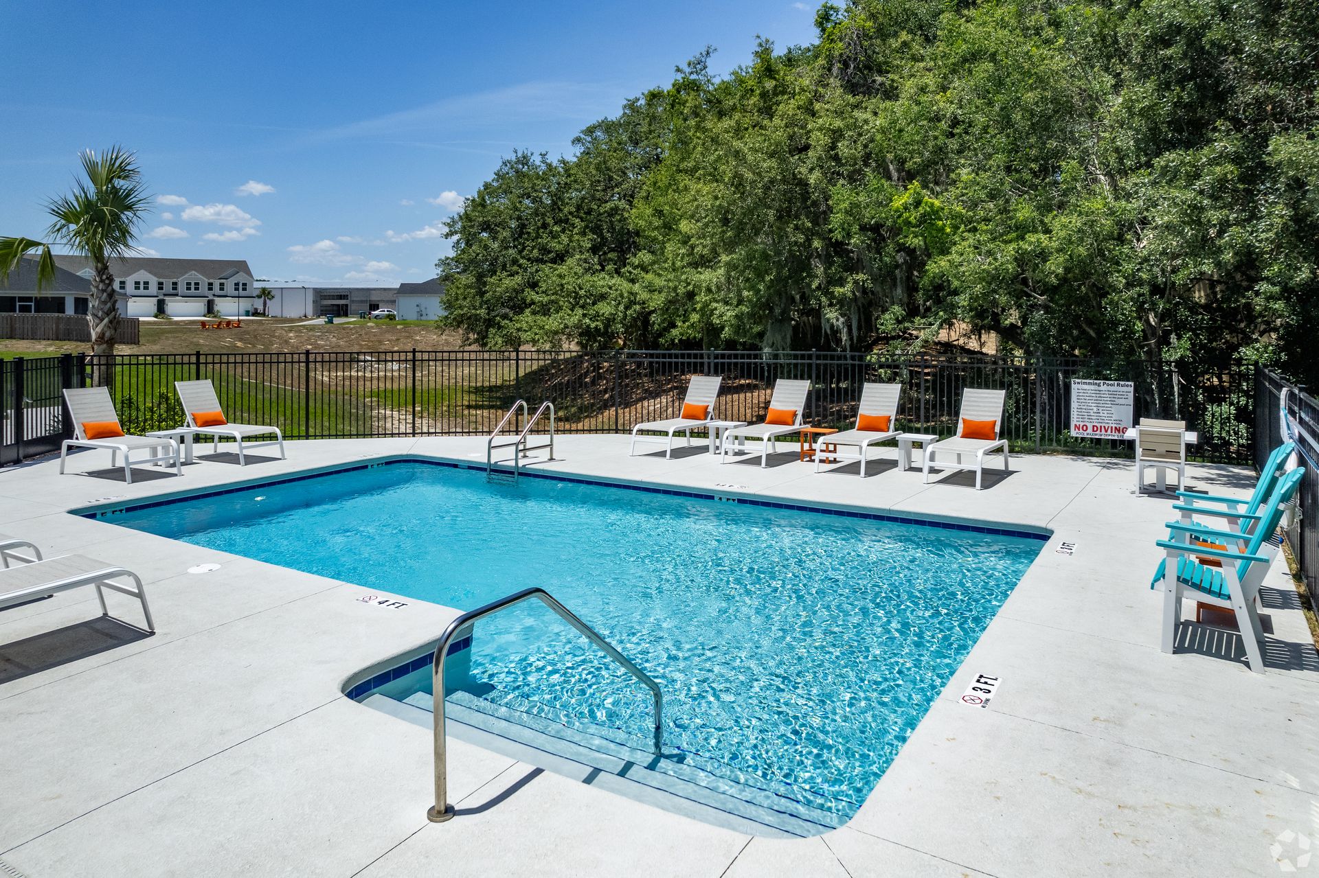 A large swimming pool surrounded by chairs on a sunny day.