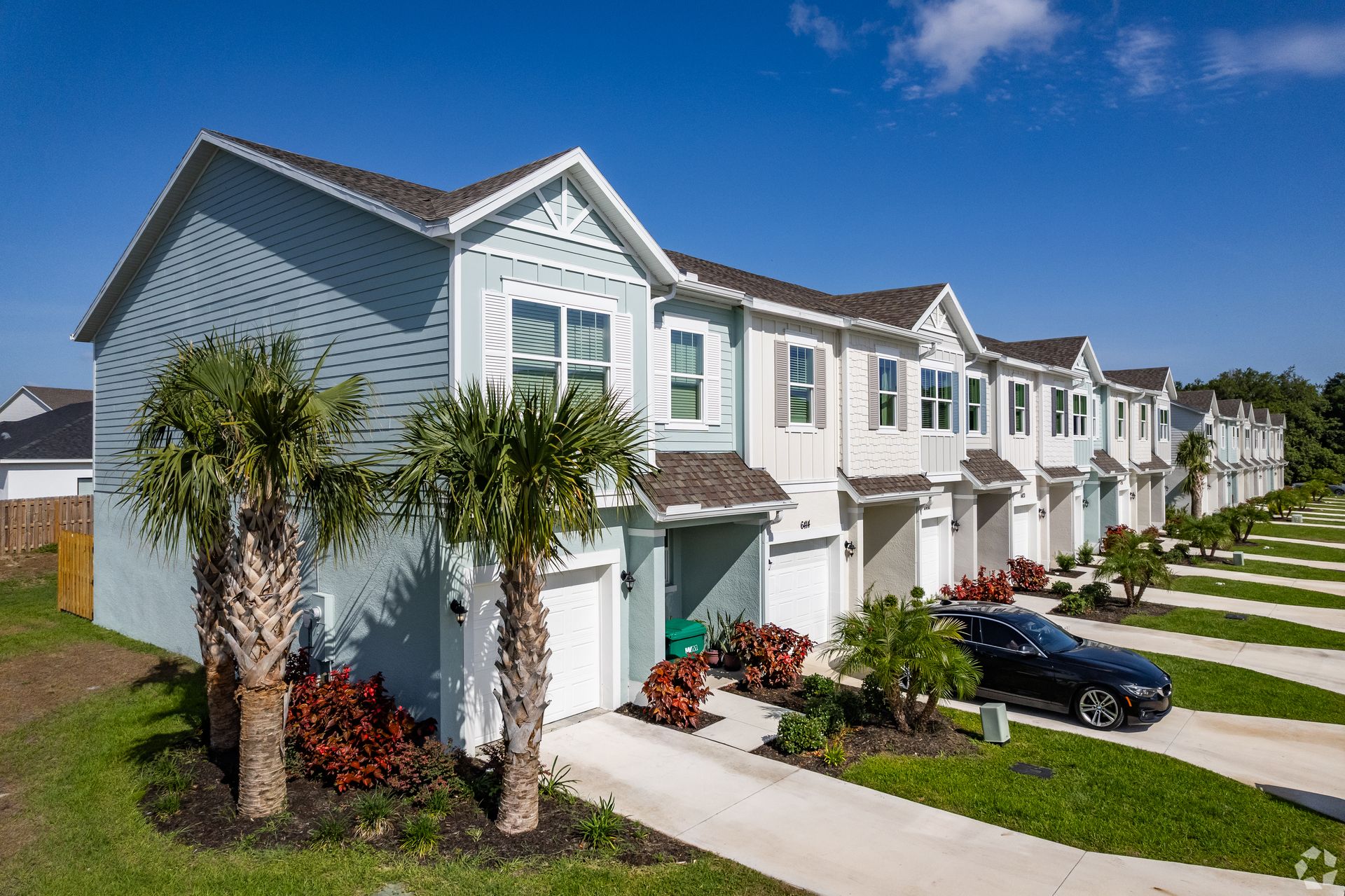 A row of houses with cars parked in front of them.