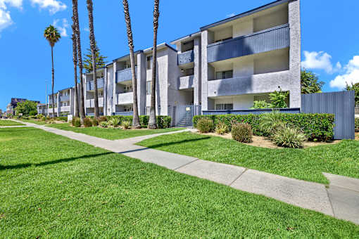 A row of modern apartment buildings with green lawns in front.