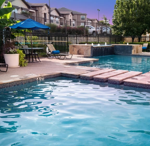 a swimming pool with chairs and umbrellas near a resort style pool
