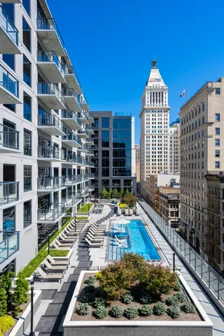 Luxurious urban apartment complex with sleek balconies overlooking a stunning rooftop pool and vibrant city skyline.