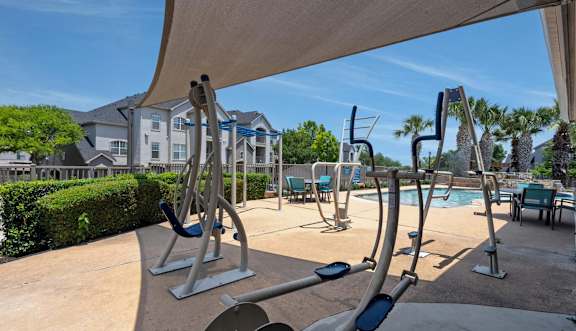 A gym with exercise equipment and a pool in the background.