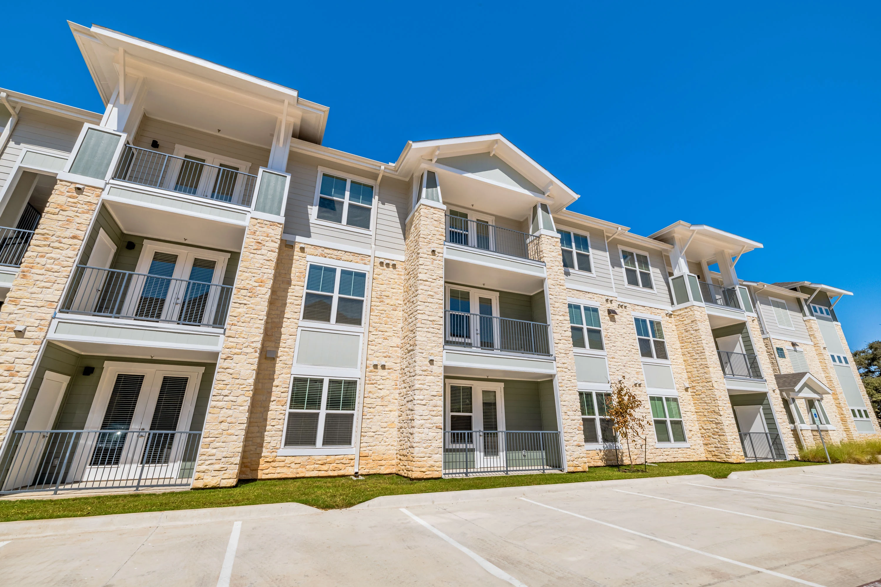 Modern apartment complex with balconies under a clear blue sky.