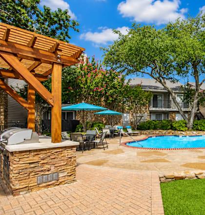 A pool surrounded by a patio and trees.