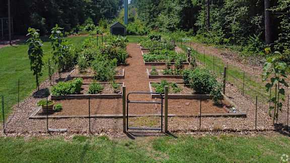 A garden with a fence and vegetables growing in it.