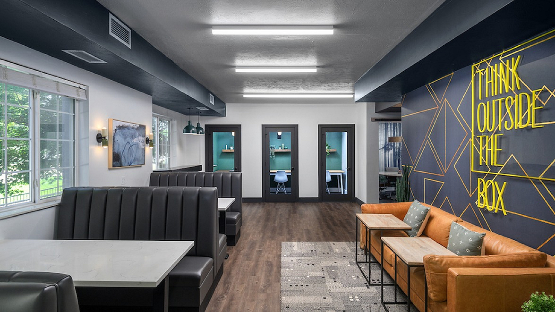 Modern co-working space with sleek booths, bold wall art, and comfortable seating, emphasizing creativity and collaboration.