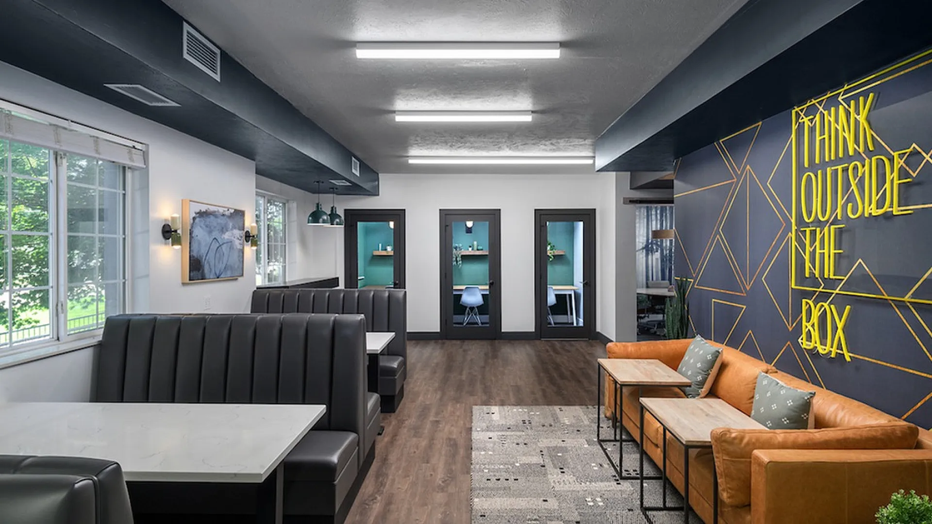 Modern co-working space with sleek booths, bold wall art, and comfortable seating, emphasizing creativity and collaboration.
