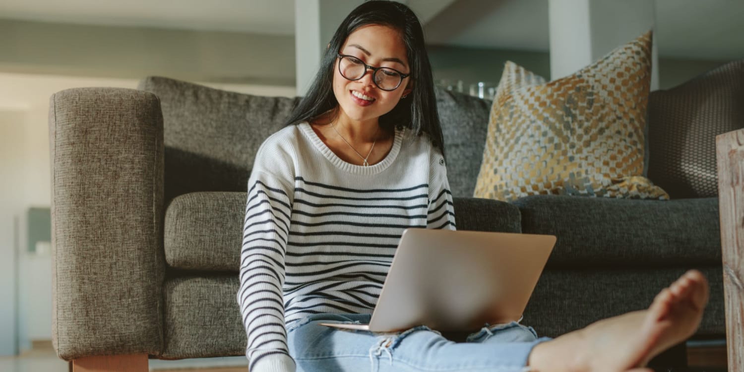 Resident sitting on the floor in her apartment while on her laptop at The Adair in Charlotte, North Carolina