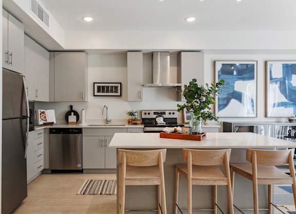 a kitchen with stainless steel appliances and an island with four chairs at Paperbox Lofts, Salt Lake City, UT