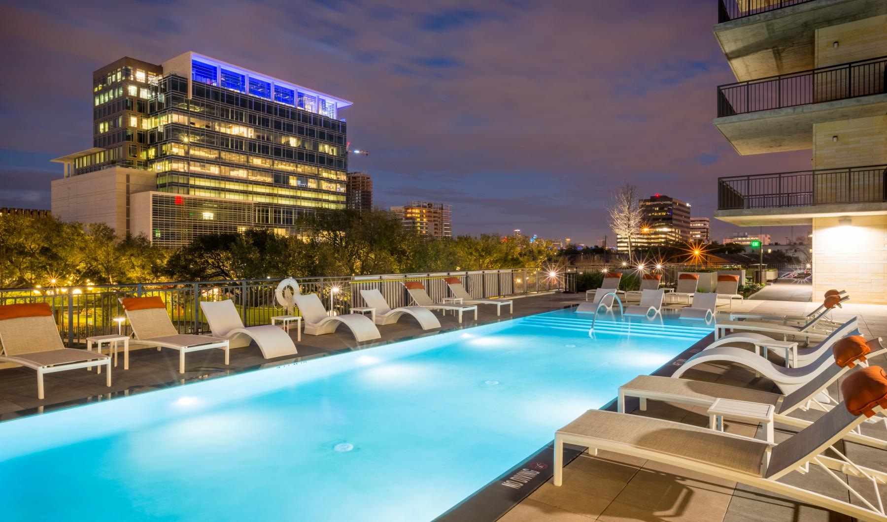 Pool with lounge chairs at Avenue Grove apartments in Houston, TX.