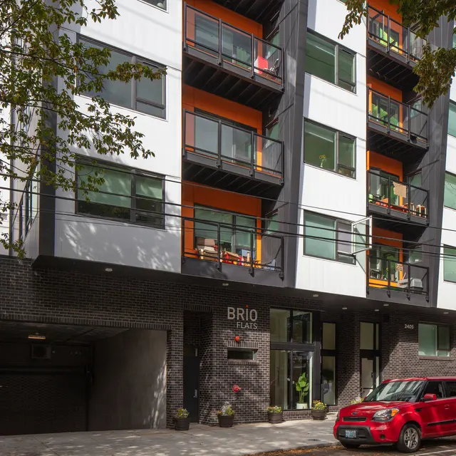Modern apartment building with a mix of white, black, and orange exterior and balconies.