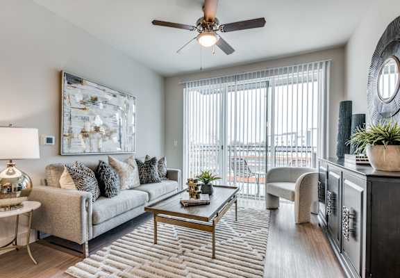 A living room with a grey couch, a coffee table, and a ceiling fan.