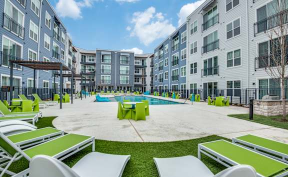 A pool surrounded by lounge chairs in a courtyard.