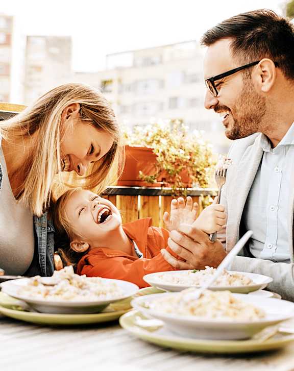 A family of three is having a meal together at an outdoor restaurant.