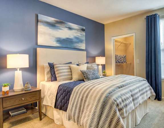 A bedroom with a large bed and a painting on the wall.